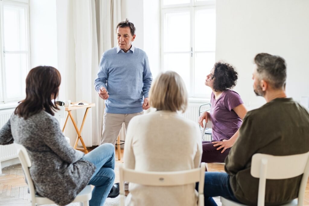 A man talking to other people during group therapy.